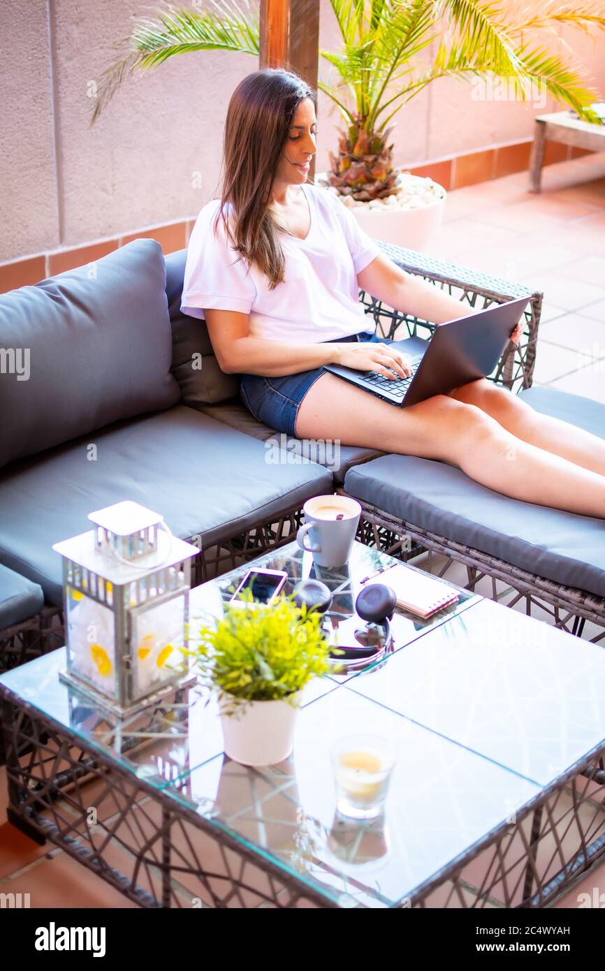 Schönes Mädchen mit einem Laptop auf einer Chaiselongue sitzen, eine Frau im Urlaub, Jobsuche Stockfoto