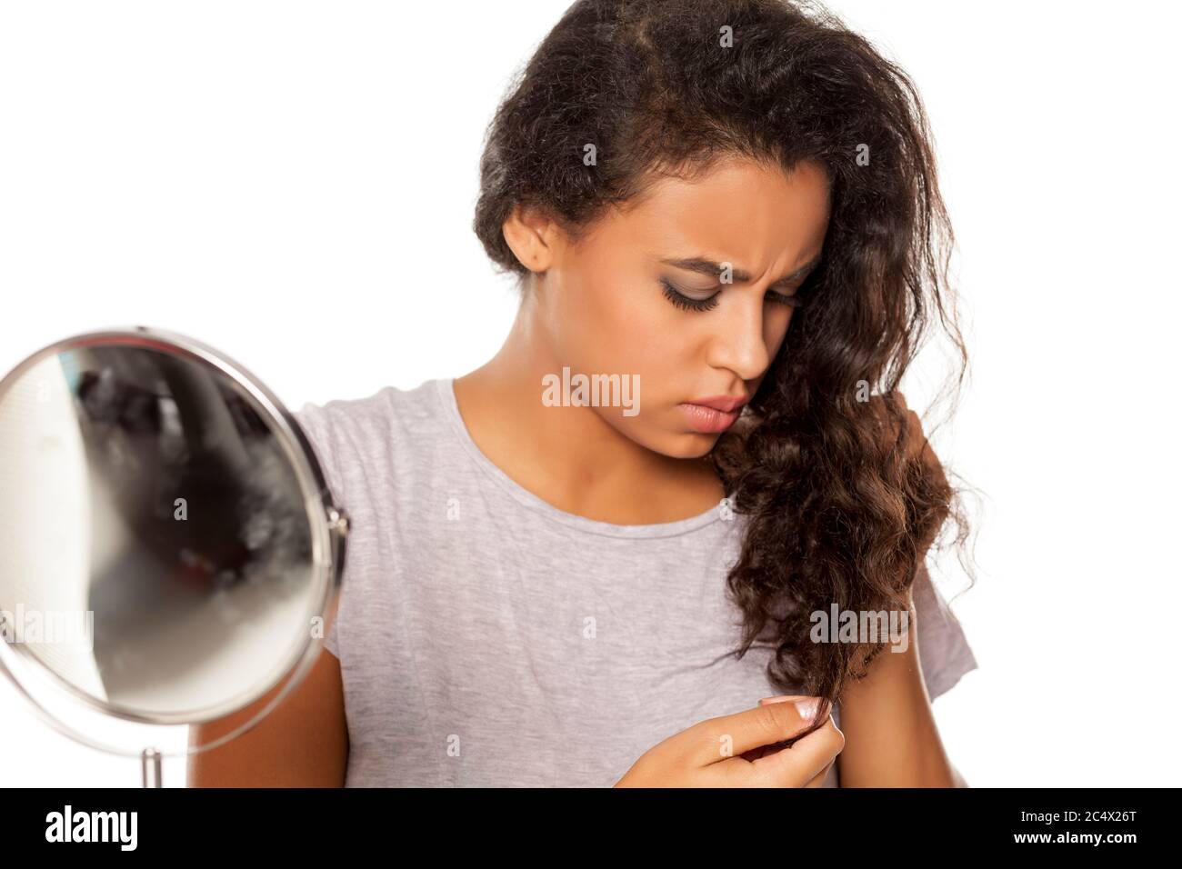 Porträt der jungen dunkelhäutigen Frau mit Haarspaltproblem auf weißem Hintergrund Stockfoto