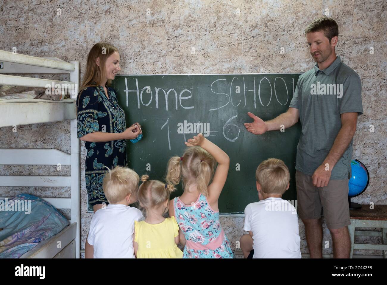 Eltern lehren ihre Kinder an der Tafel in ihrem Haus. Heimschule. Stockfoto