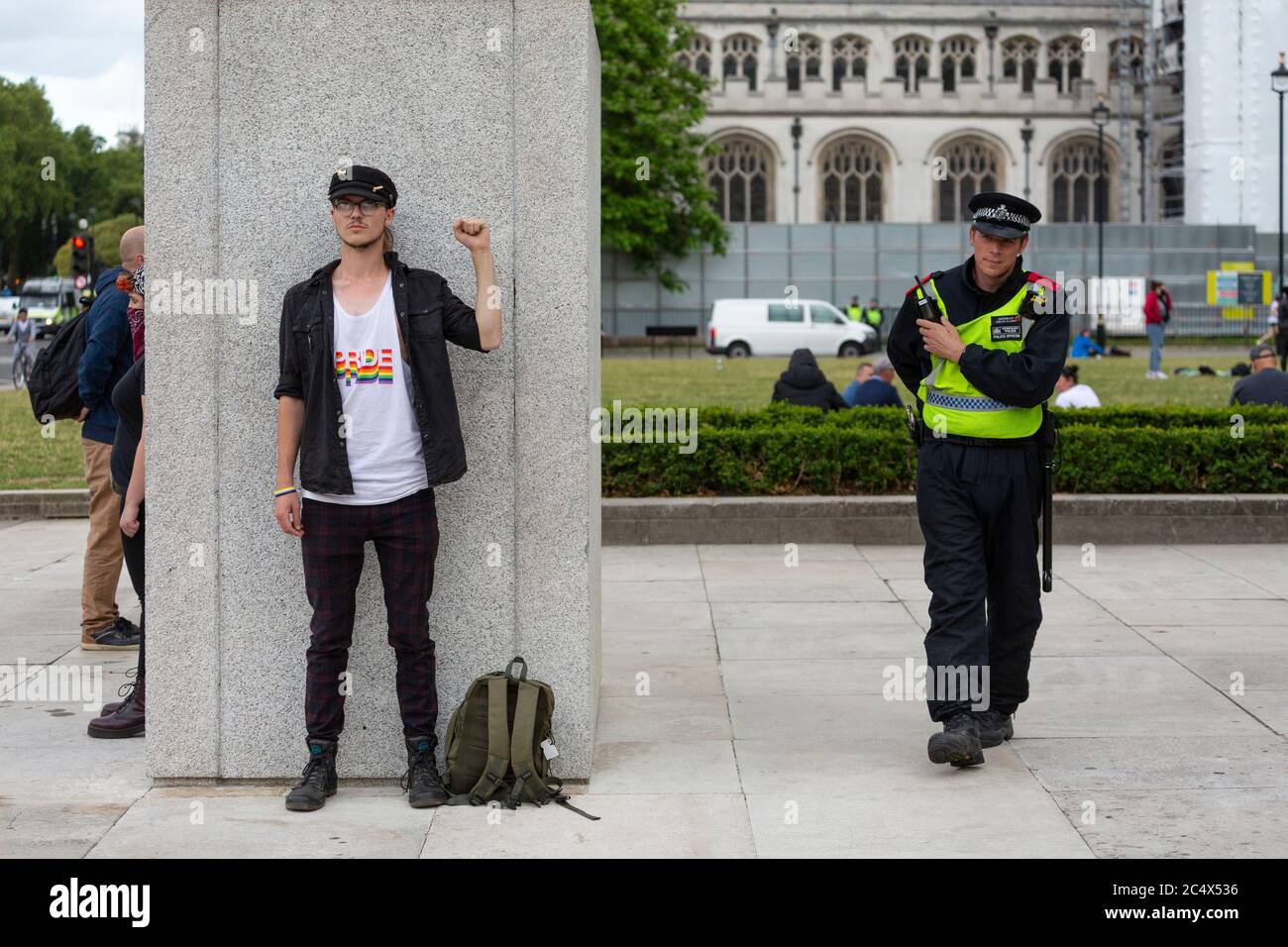Ein junger Mann steht mit erhobener Faust von einer Winston Churchill Statue, Black Lives Matter Demonstration, Parliament Square, London, 21. Juni 2020 Stockfoto