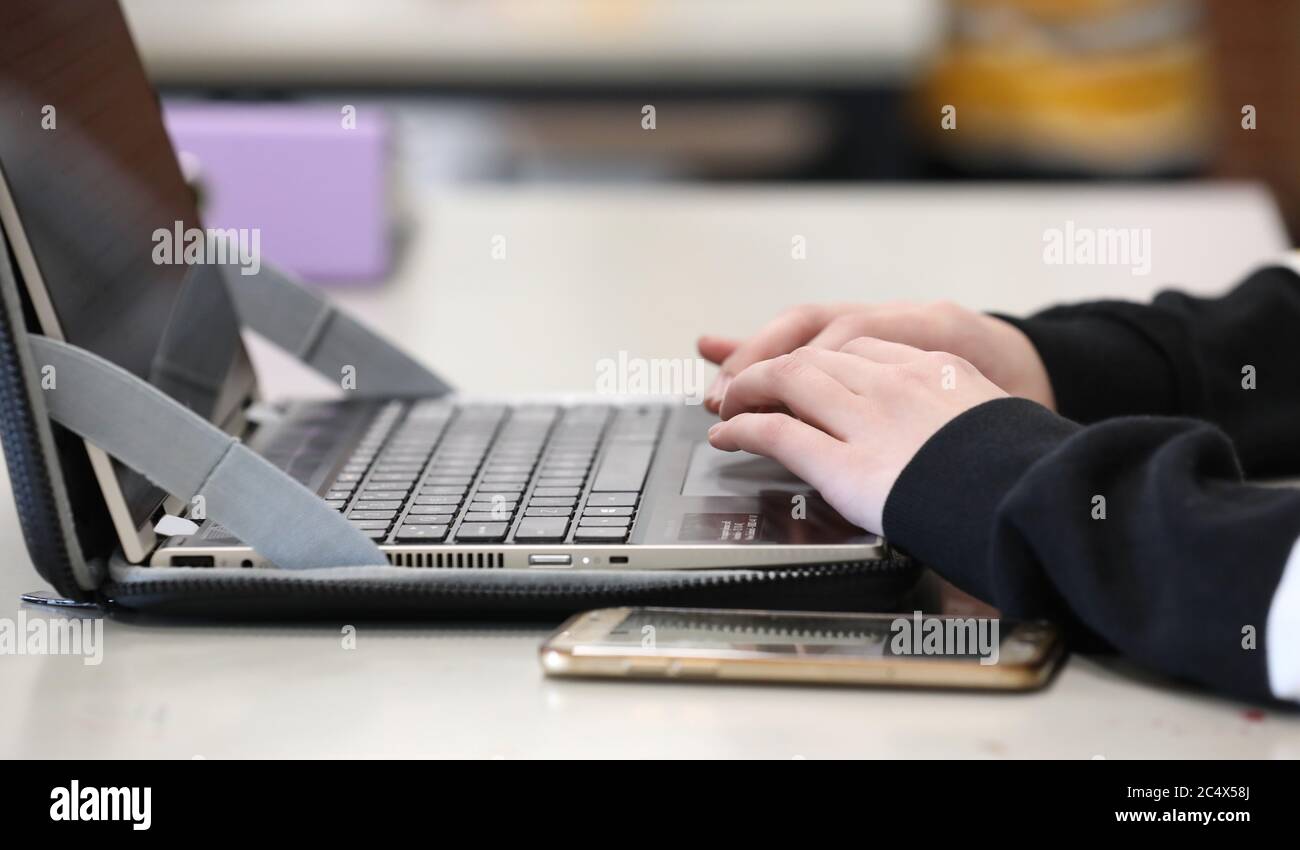 Der moderne Lernende. Ein Schüler in einer High School oder Universität Klassenzimmer Umgebung tippen auf einem Computer oder Laptop-Tastatur mit Telefonen in der Nähe. Stockfoto