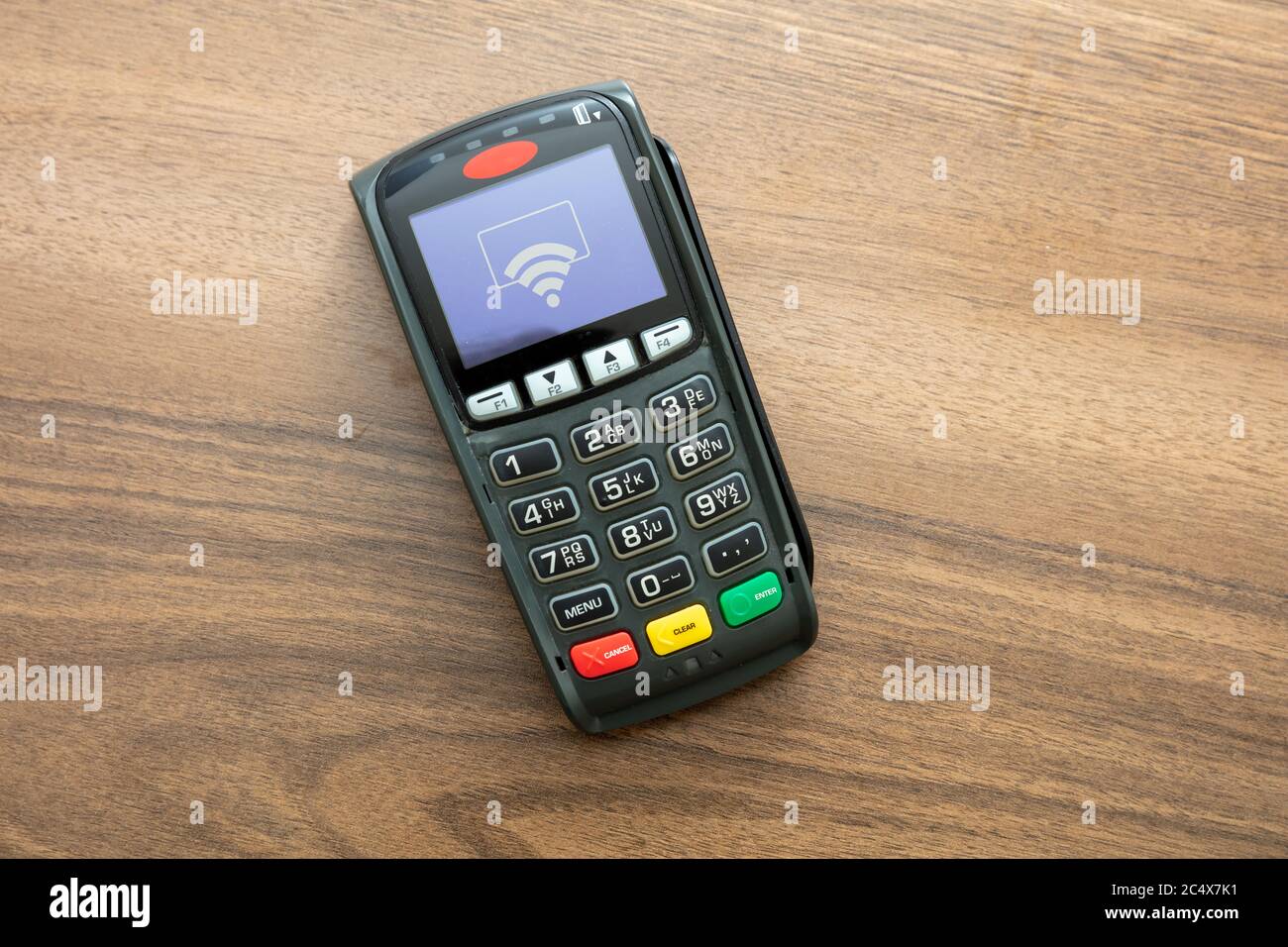 POS-Terminal isoliert auf Holzhintergrund, Draufsicht.Terminal-Kassenautomat für kontaktloses Bezahlen mit Kreditkarte. Bankausstattung, NFC. Stockfoto