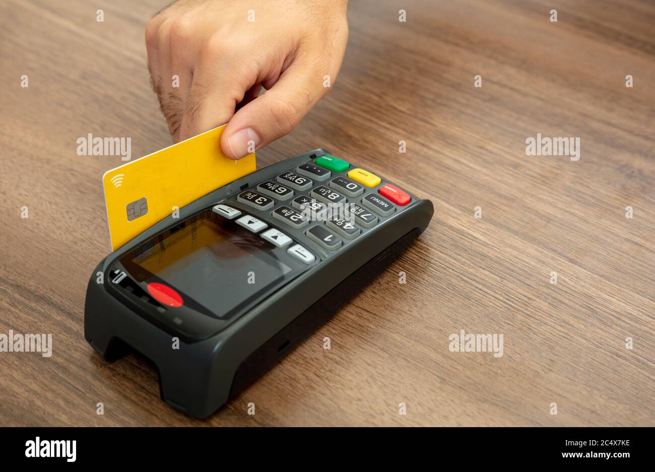 Hand wischen eine Kreditkarte in einem POS-Terminal auf Holz-Theke Hintergrund, Nahaufnahme.Terminal-Kasse Maschine für bargeldlose Zahlung. Stockfoto