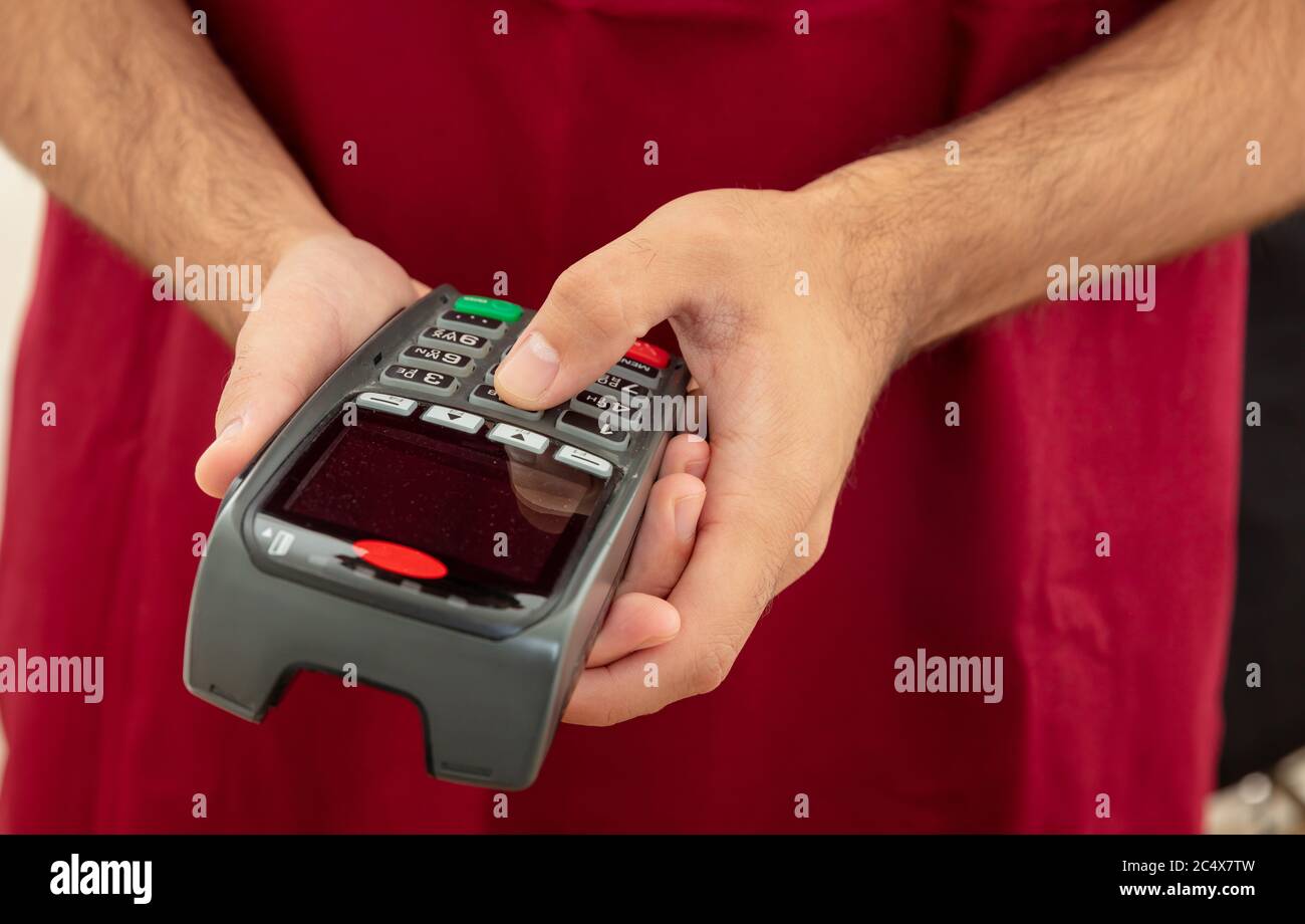 Mann hält eine Zahlung Swipe Maschine und Eingabe, Nahaufnahme. Kreditkartenleser, Kassenterminal-Bezahlkonzept. Stockfoto