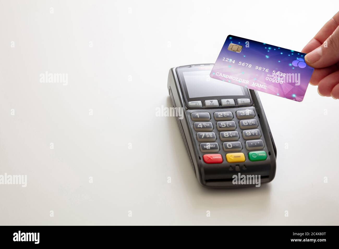 Bezahlung mit NFC-Technologie. Hand hält eine Kreditkarte über einem POS-Terminal isoliert auf weißem Hintergrund, Nahaufnahme Ansicht.Terminal Kasse Maschine Stockfoto