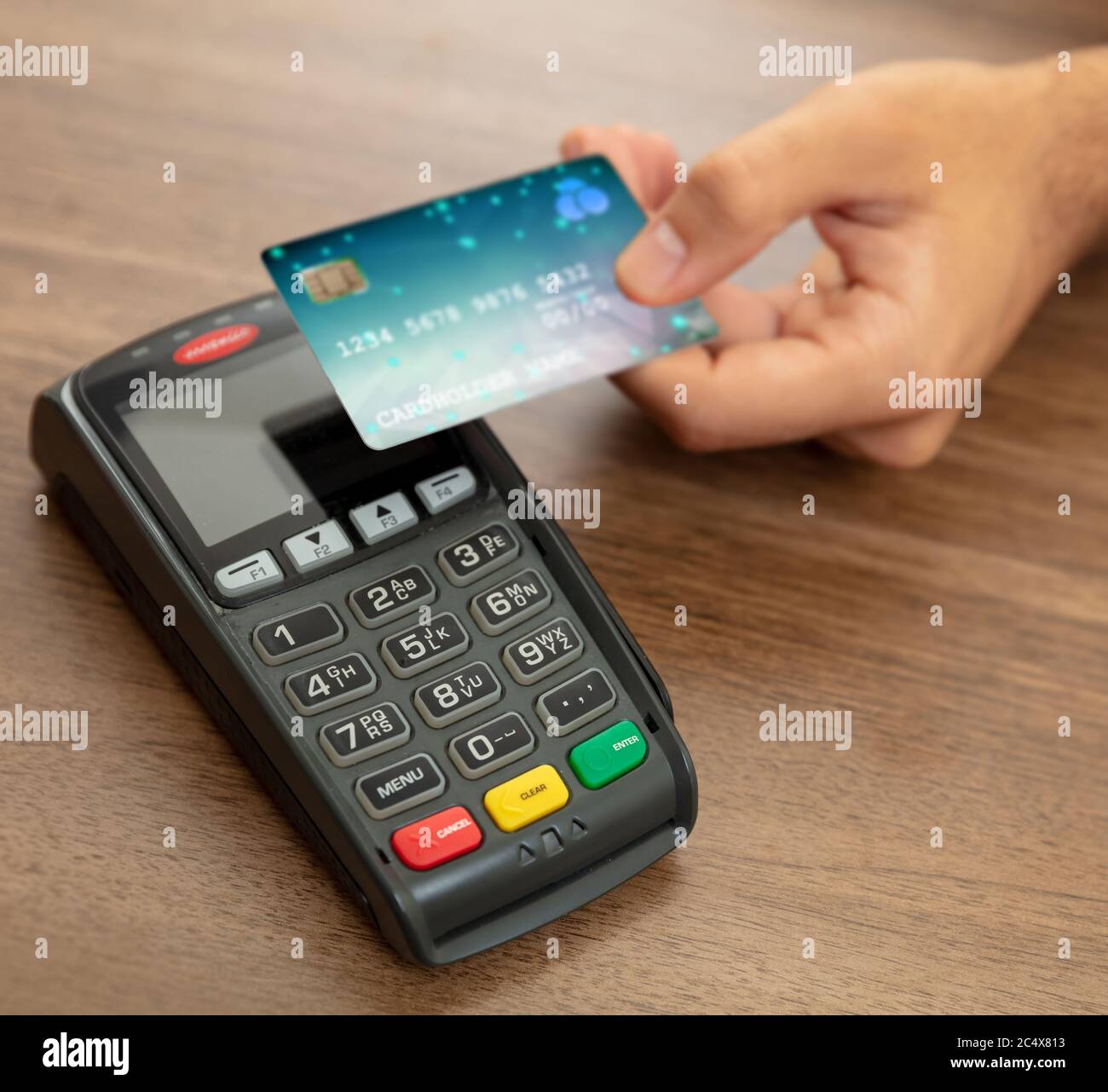 Bezahlung mit NFC-Technologie. Hand hält eine Kreditkarte über einem POS-Terminal, Holztheke Hintergrund, Nahaufnahme Ansicht.Terminal Kasse Maschine fo Stockfoto