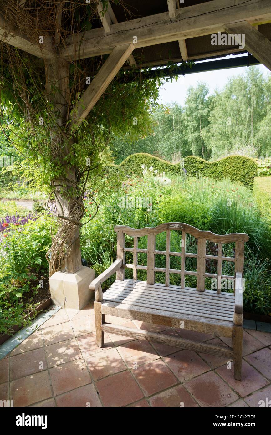 Ein dekorativer Gartenstuhl aus Holz, der auf einer Terrasse vor einem  großen Garten im Hintergrund steht. Harrogate, North Yorkshire, England,  Großbritannien Stockfotografie - Alamy