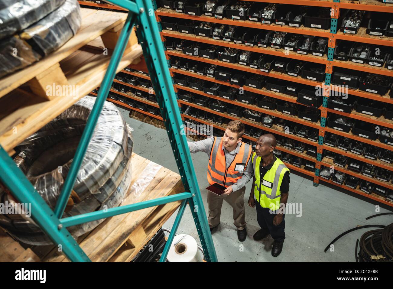 Zwei männliche Fabrikarbeiter mit digitalem Tablet, die den Bestand in der Fabrik überprüfen Stockfoto