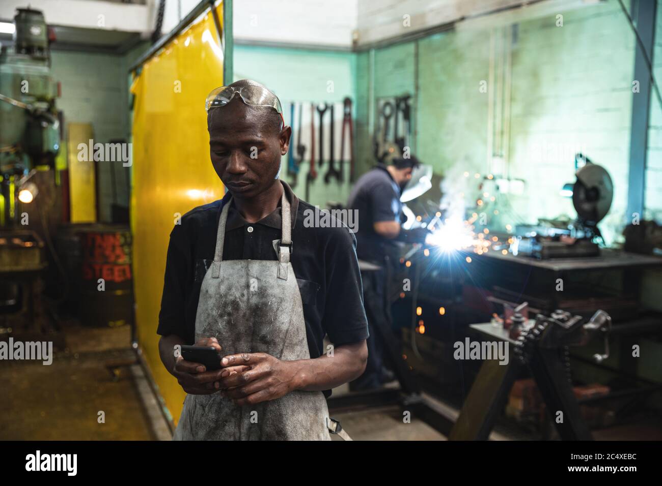 Männliche Fabrik trägt Schürze mit Smartphone in der Fabrik Stockfoto