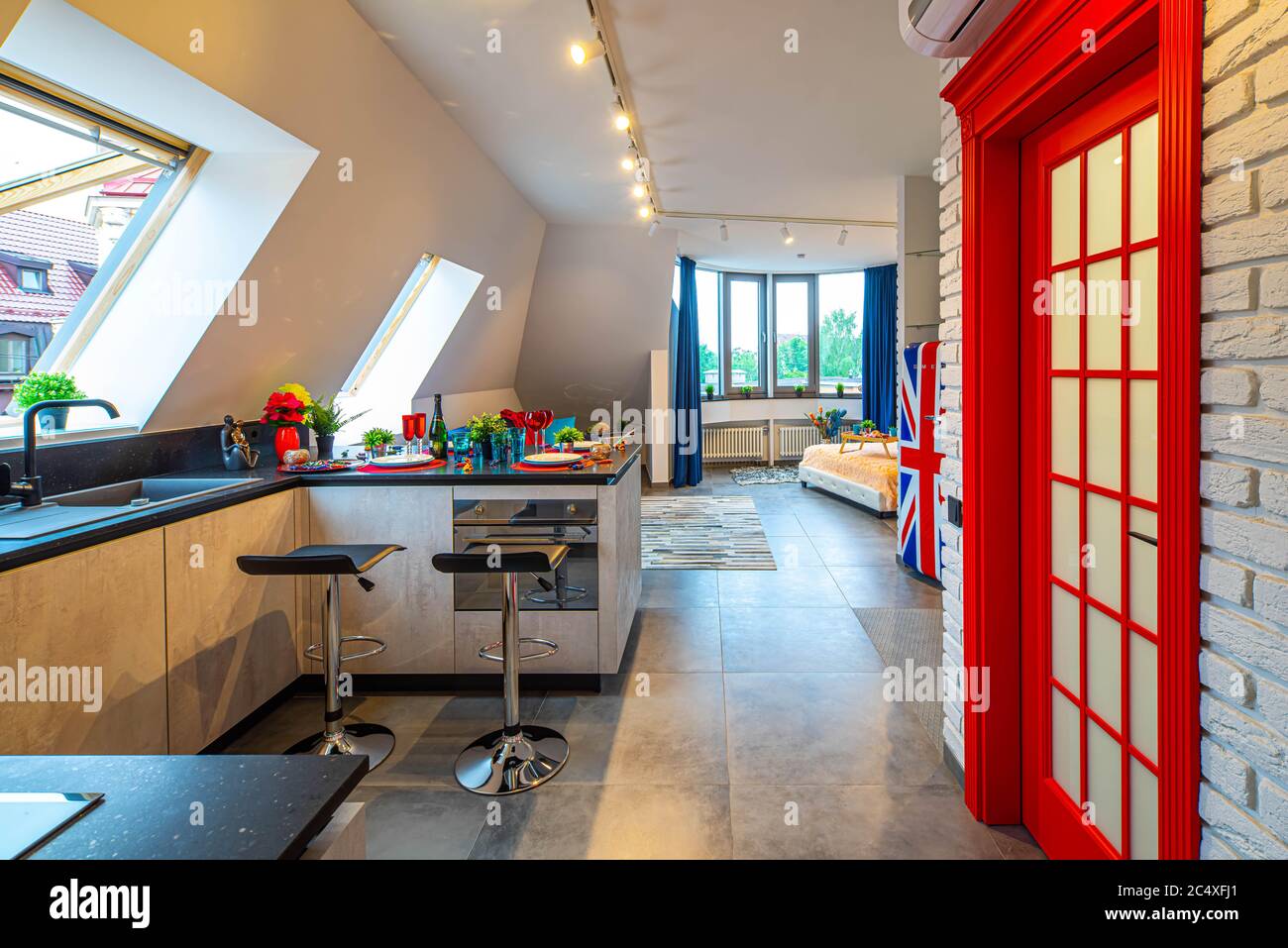 Moderne Loft-Interieur im britischen Stil der Luxus-Studio-Wohnung. Essen und Getränke auf dem Tisch. Gemütliches Bett. Ziegelwand. Stockfoto