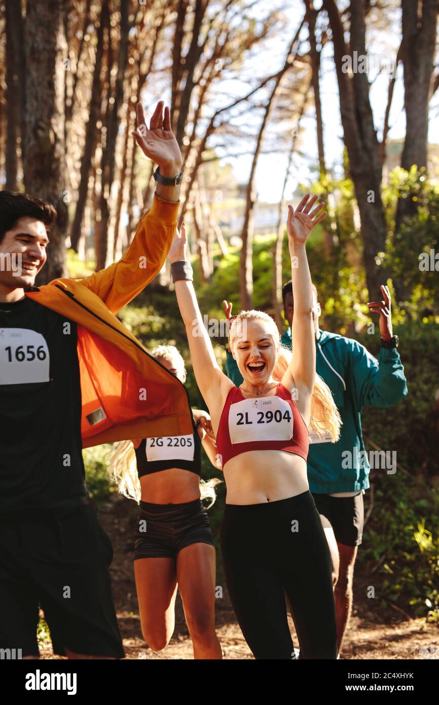 Gruppe von Männern und Frauen feiern nach dem Ende des Rennens im Wald. Profis Athleten begeistert nach dem Sieg das Rennen. Stockfoto