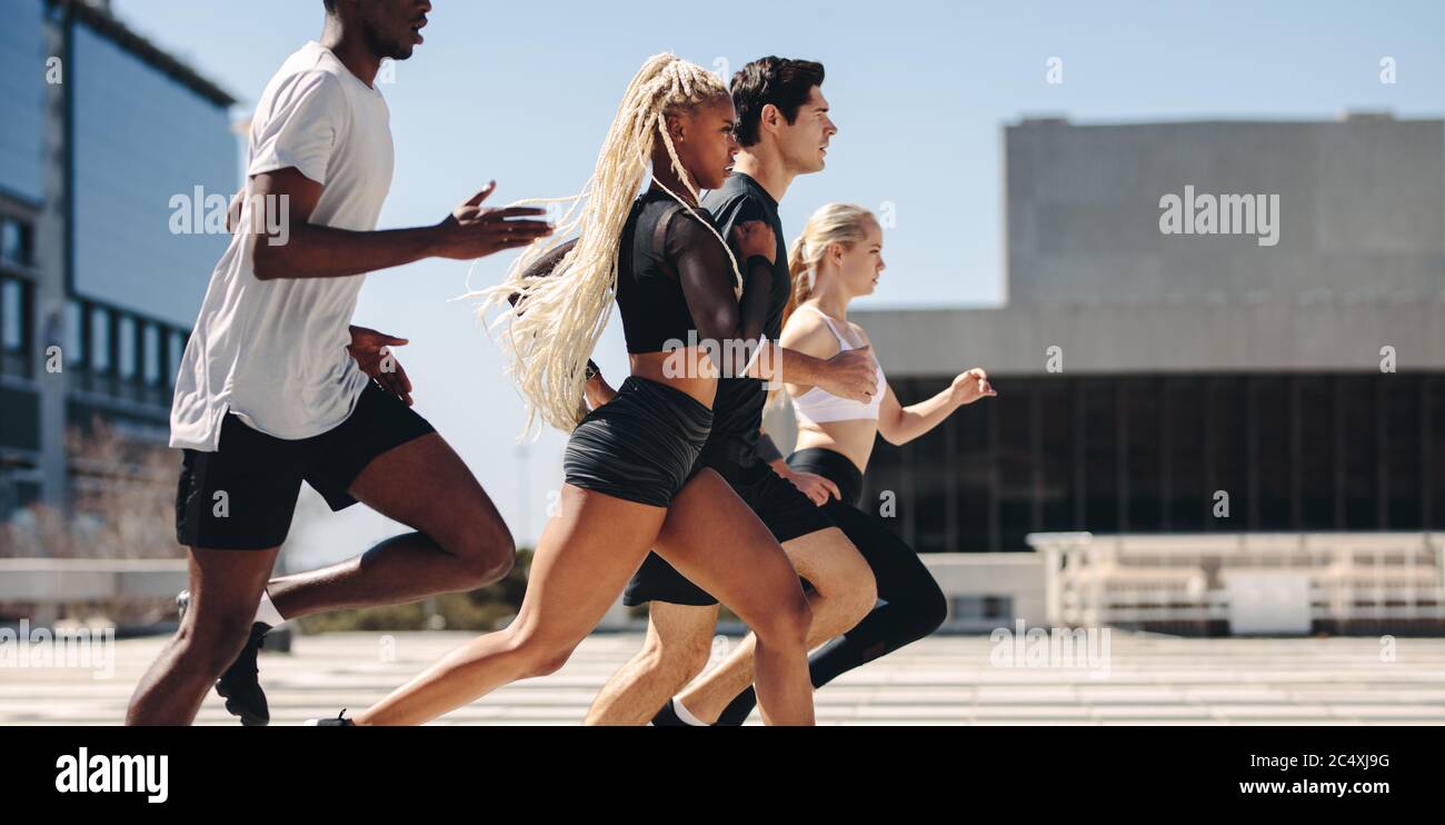 Eine Gruppe von Leuten, die gemeinsam in der Stadt laufen. Diverse Straßenläufer laufen in der Stadt. Stockfoto