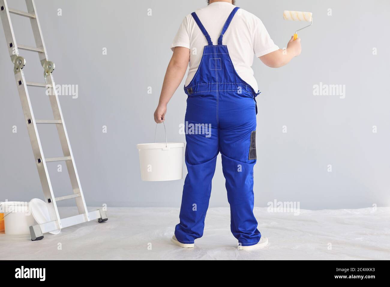 Malermalerei. Lustiger männlicher Maler mit einem Rollschuh stehend malt im Hintergrund. Stockfoto