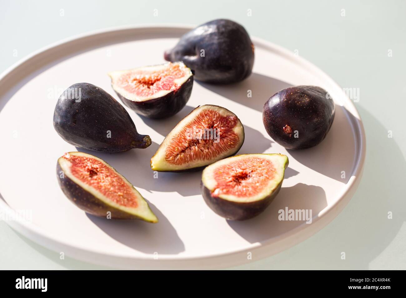 Horizontales Bild von Feigen in weißer Keramikplatte unter harten Lichtbedingungen aufgenommen. Stockfoto