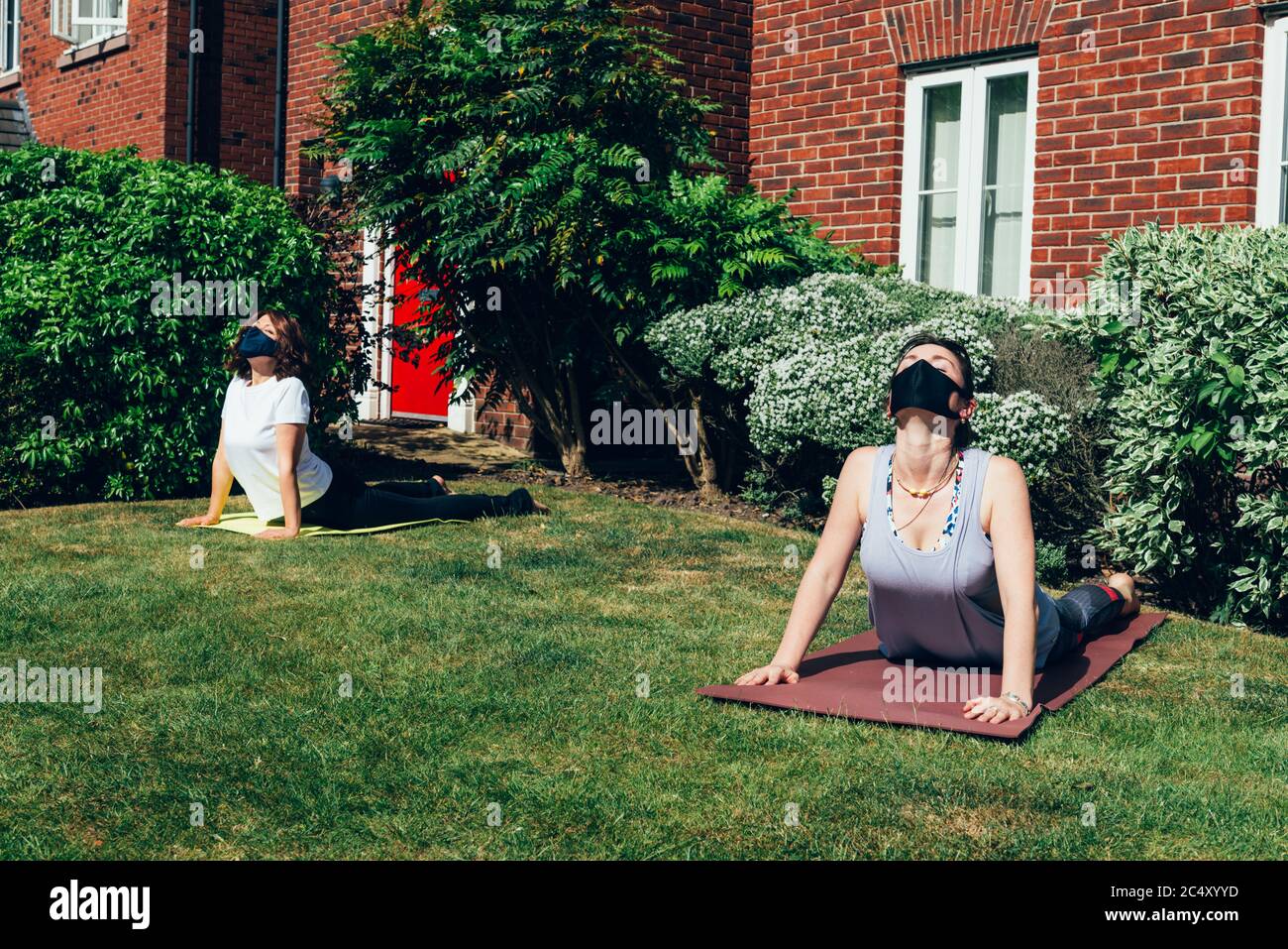 Yoga im Garten mit sozialer Distanz trainieren Stockfoto