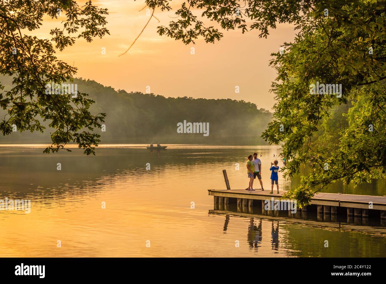 Familienfoto-Moment bei einem feurigen Sonnenuntergang am Ufer des Fort Yargo State Park Campground in Winder, Georgia. (USA) Stockfoto