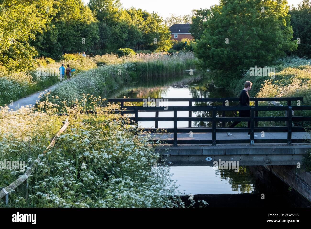 Ein Mann, der eine Brücke über den Grantham Canal überquert und andere Menschen, die auf einem Fußweg spazieren, Gamston, West Bridgford, Nottinghamshire, England, Großbritannien Stockfoto