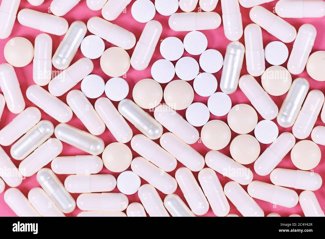 Weiße Kapsuel und harte Pillen auf rosa Hintergrund Stockfoto