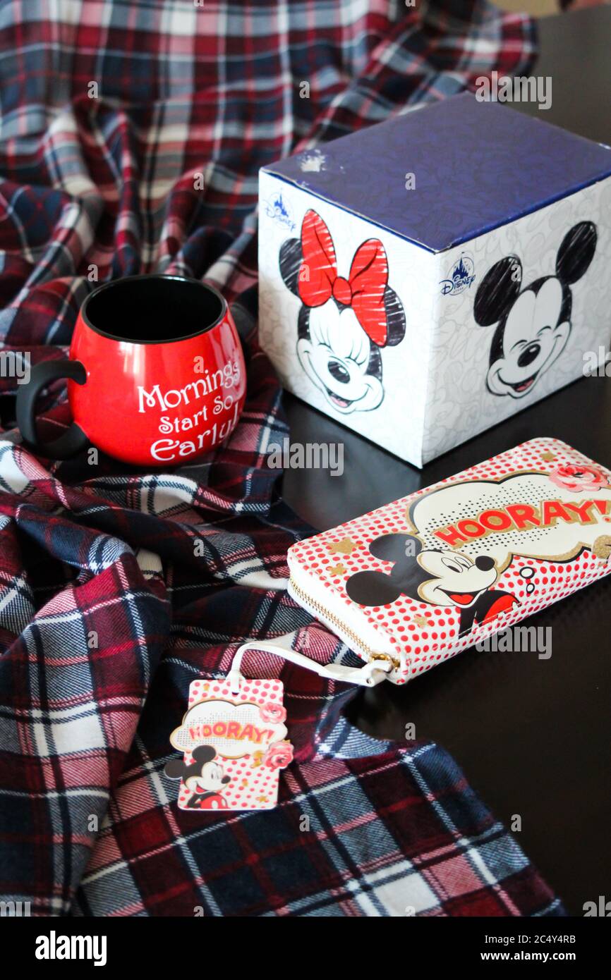 mickey Maus Tee Tasse und Geldbörse steht auf einem schwarzen Tisch Stockfoto