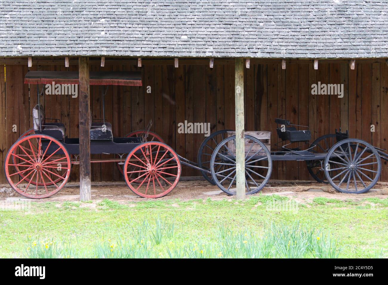 Zwei schöne Vintage Pferdewagen Trap Fahrzeug neben einem rustikalen Stall Stall Gebäude Stockfoto