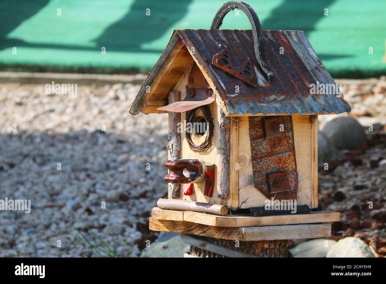 Ein einzigartiges rustikales handgemachtes Zinndach Vogelhaus auf einem Steinboden Stockfoto