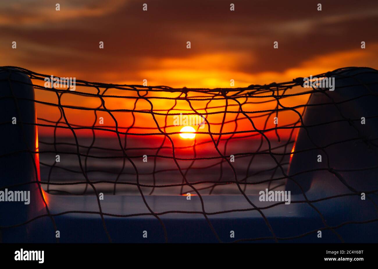 Farbenfrohe, verschwommene Meeresaufgänge durch ein Fischernetz auf einem Tretboot am Strand von Rivazzurra (Rimini/Italien) Stockfoto