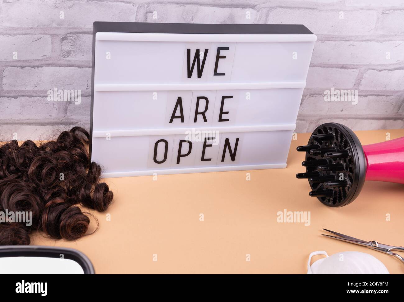 'Wir sind offen' Schild für Friseurladen und Friseursalon, nach Quarantäne, auf gelbem Hintergrund mit Gesichtsmaske, Schere und Haarbläser, Wiedereröffnung Konzept. Stockfoto