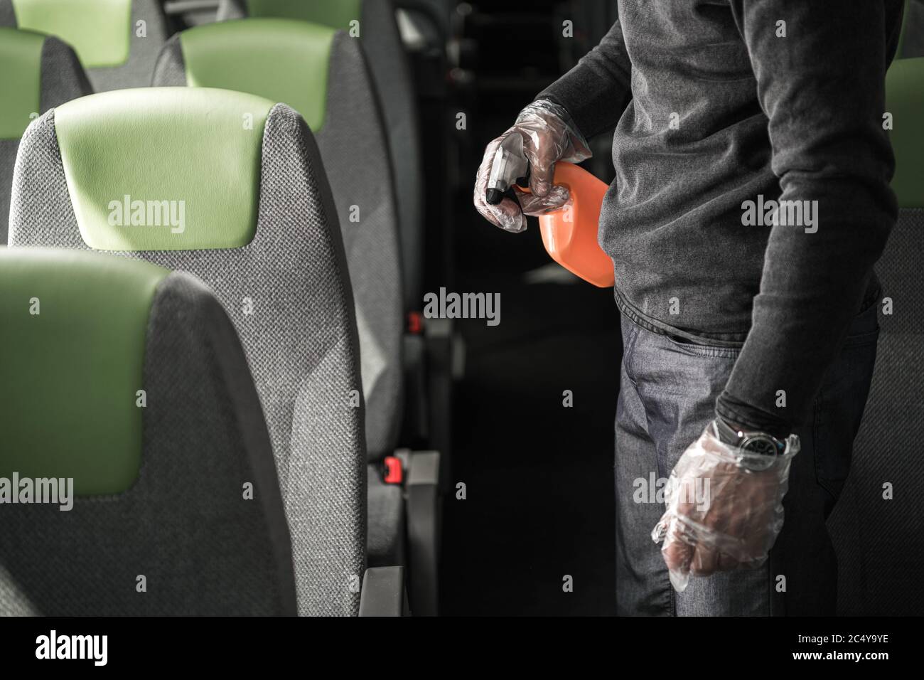 Männliche Reinigung Crew Worker Mit Sprühflasche In Der Hand Desinfektion Des Inneren Des Intercity Coach Bus. Stockfoto