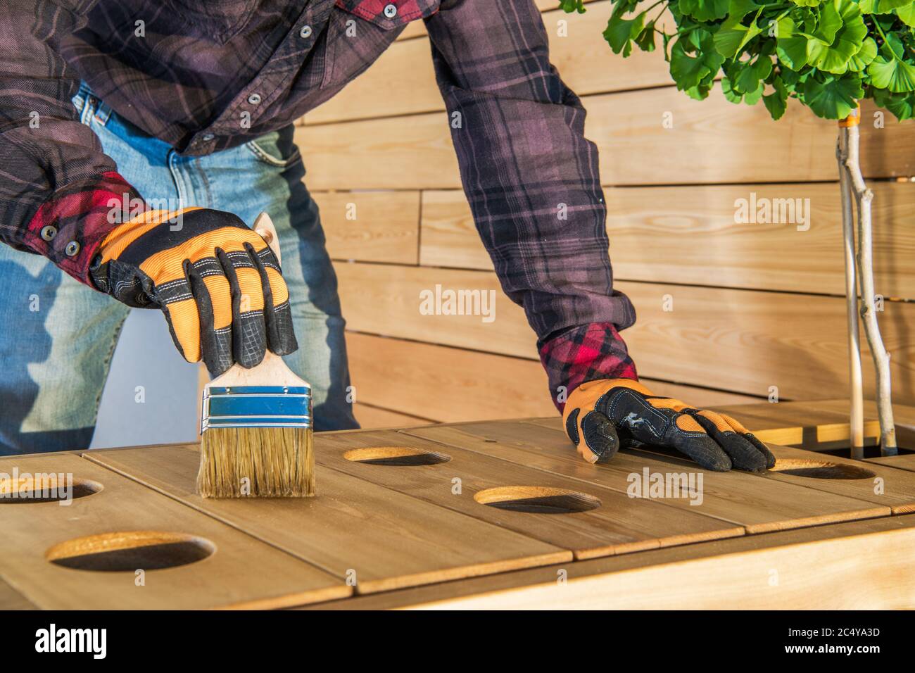 Handwerker Anwendung Mantel Öl Finish Auf Die Oberfläche Von Outdoor-Holzmöbel. Stockfoto