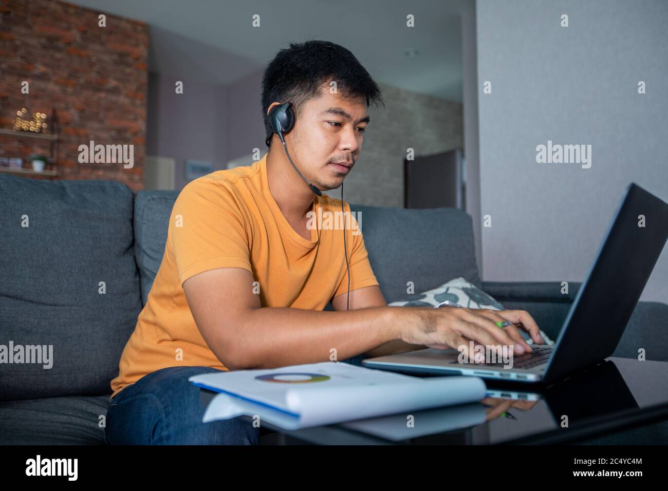 Asiatische Geschäftsleute verwenden Notebooks und tragen Kopfhörer für Online-Meetings und Arbeiten von zu Hause aus. Stockfoto