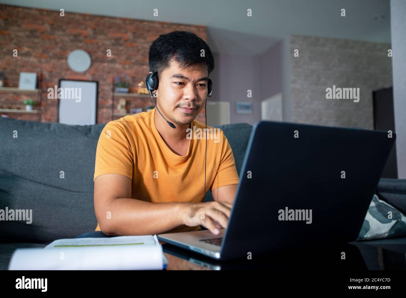 Asiatische Geschäftsleute verwenden Notebooks und tragen Kopfhörer für Online-Meetings und Arbeiten von zu Hause aus. Stockfoto