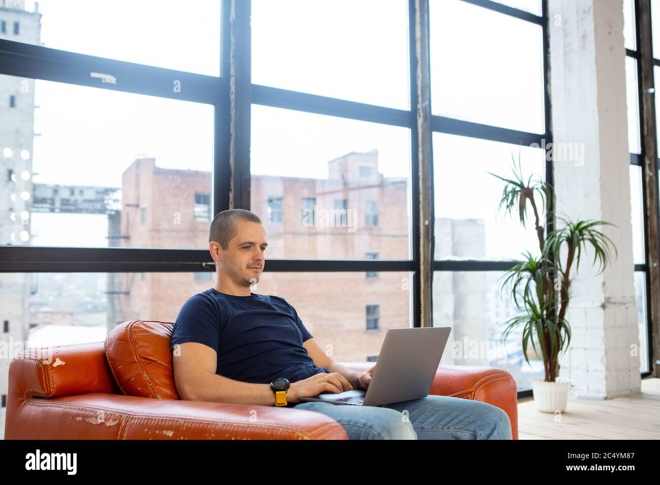 Mann Freiberufler arbeitet auf Laptop sitzen auf roten Sessel Stockfoto