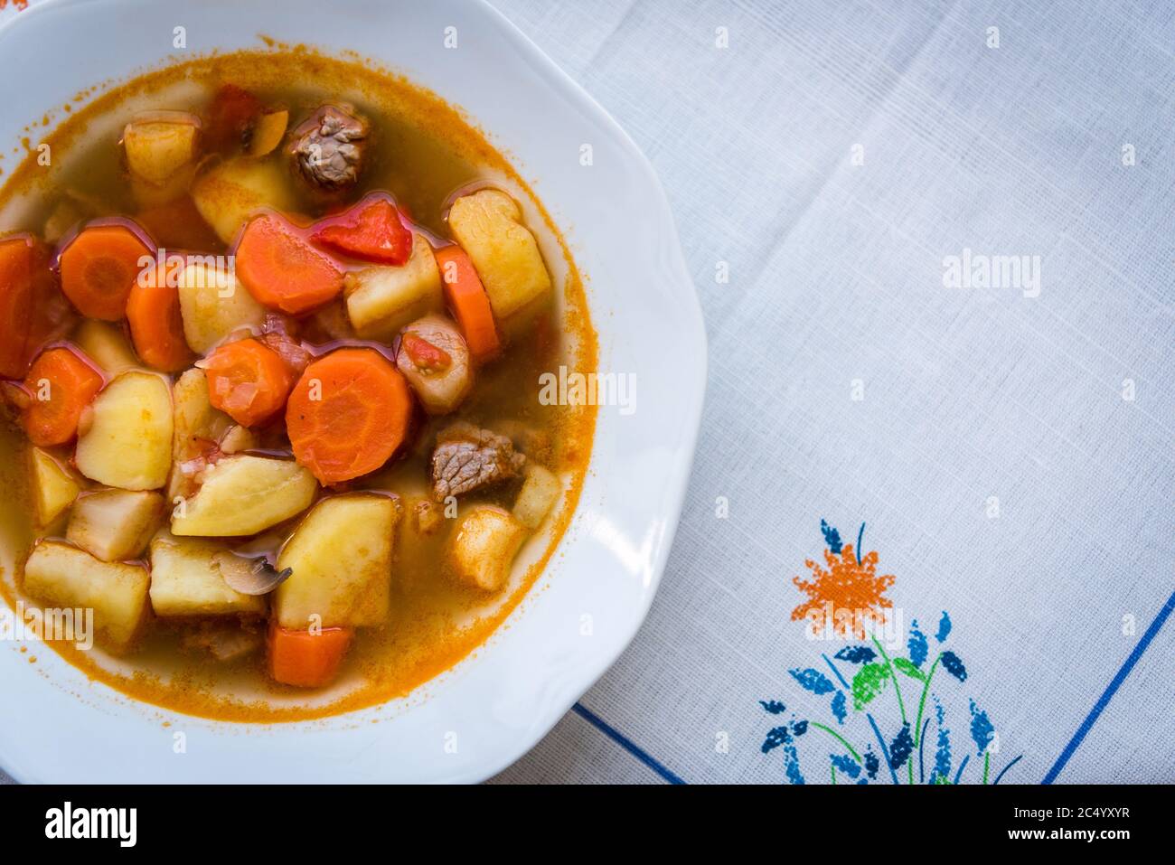 Traditionelle hausgemachte ungarische heiße Gulaschsuppe mit Mem, Kartoffeln, Karotten und Pilzen auf einem weißen Teller auf dem Tisch. Europäische Küche. Draufsicht. Stockfoto