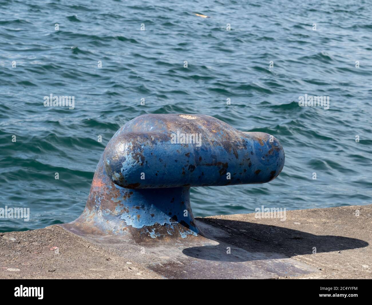 Ein rostiger Seeschiff, der Stollenstalle oder Poller auf einem festmachen soll pier am Ufer Stockfoto