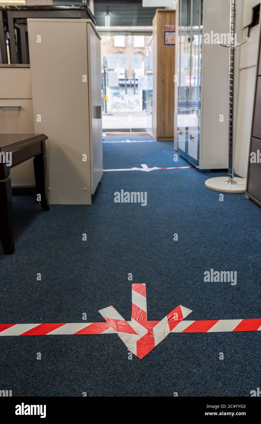 Richtmarkierungen auf dem Boden eines Möbelshops, wie es die staatlichen Regeln der sozialen Distanzierung für Einzelhändler erfordern. Stockfoto