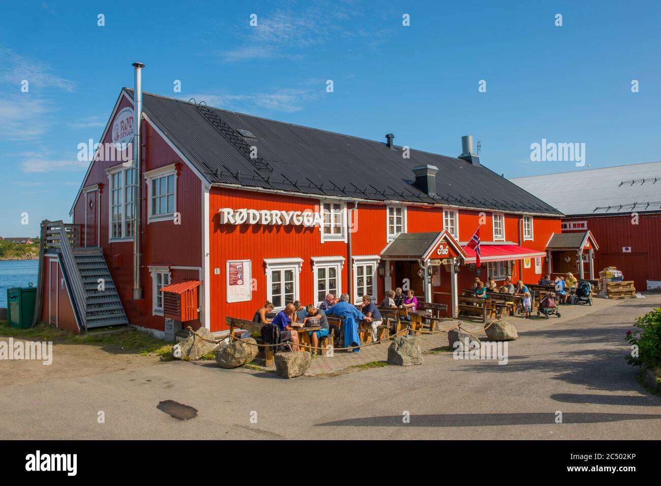 Menschen, die vor einem Pub und Restaurant in Stokmarknes, einer kleinen Stadt in der Gemeinde Hadsel in Nordland County, Lofoten Islands, Sonne genießen, Stockfoto