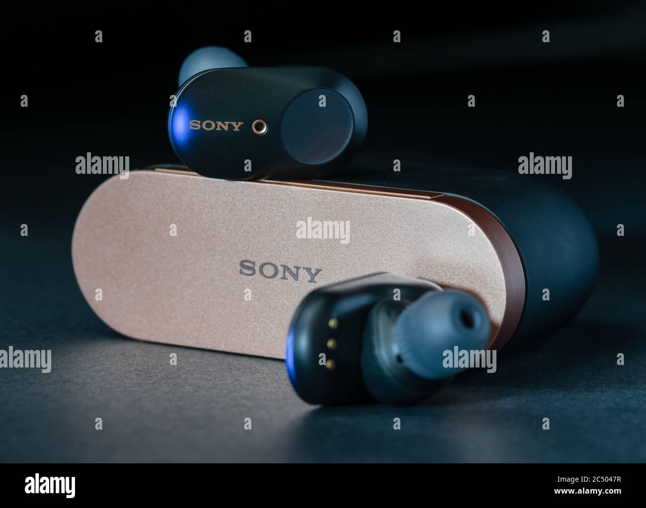 Ein Paar schnurlose Kopfhörer von Sony mit Ladegerät-Gehäuse mit dunklem Hintergrund. Stockfoto