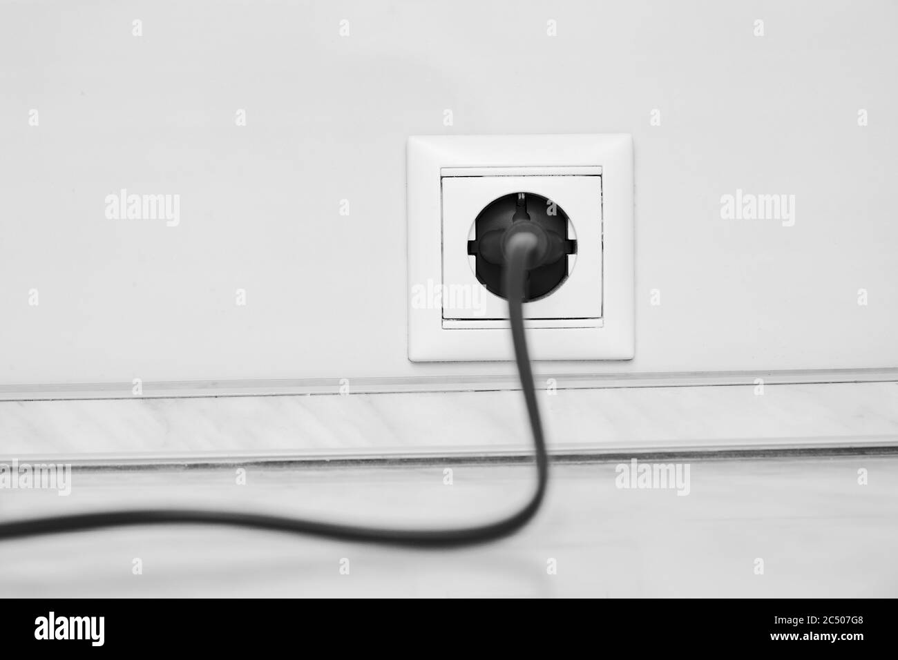 Weiße Steckdose und ein eingestecktem Netzkabel Weißer Wandhintergrund Stockfoto
