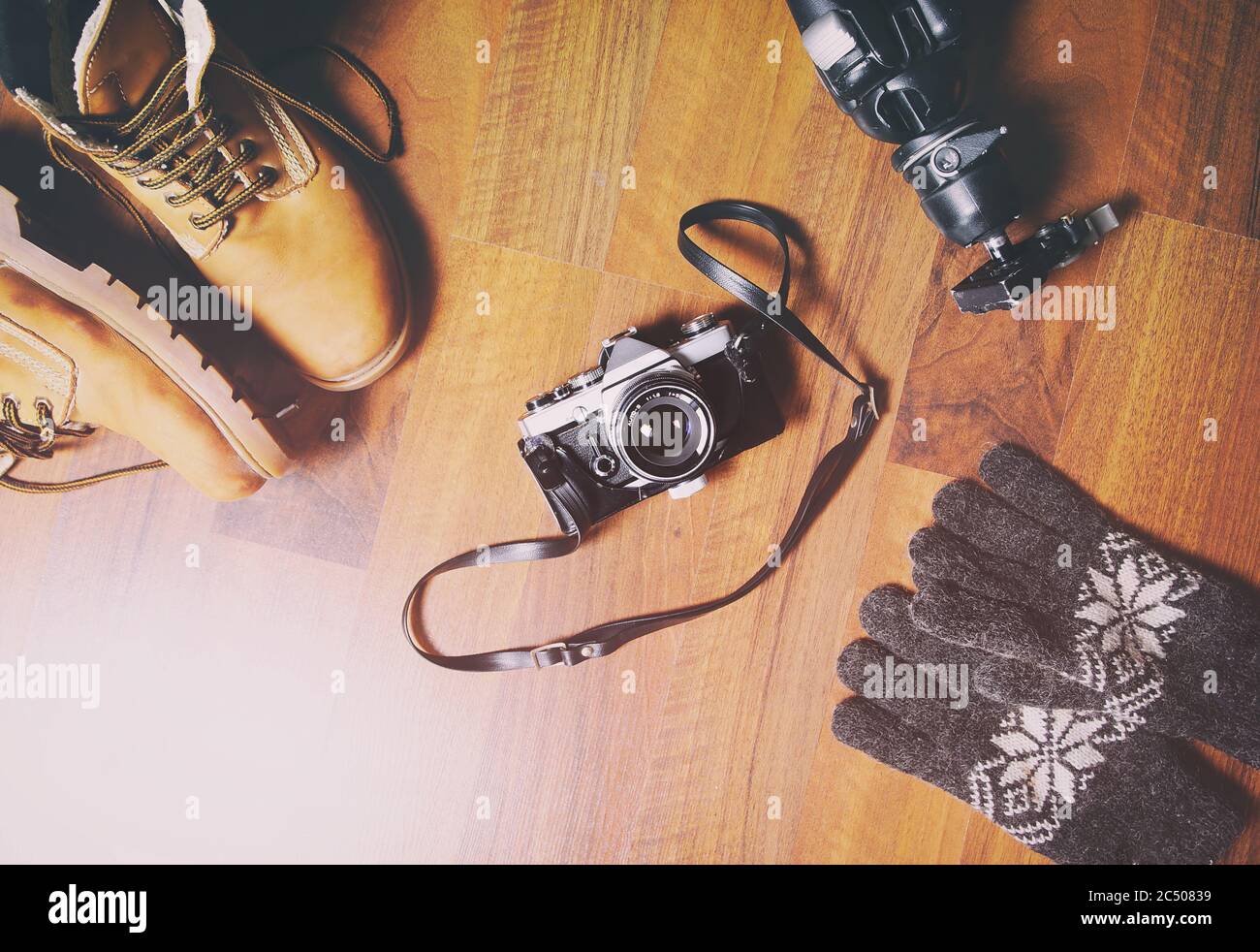 Reiseaccessoires auf Holzhintergrund gesetzt: Wanderschuhe aus Leder, Vintage-Kamera, Stativ. Stockfoto