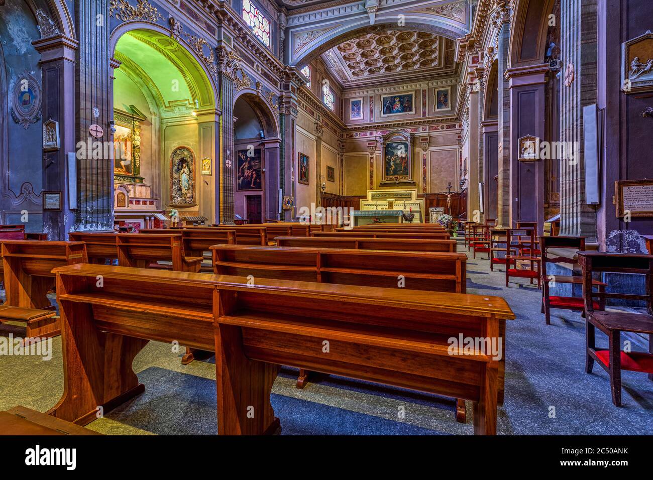 Holzbänke in einer Reihe innerhalb von San Giovanni Battista - alte Pfarrkirche in Alba, Italien. Stockfoto