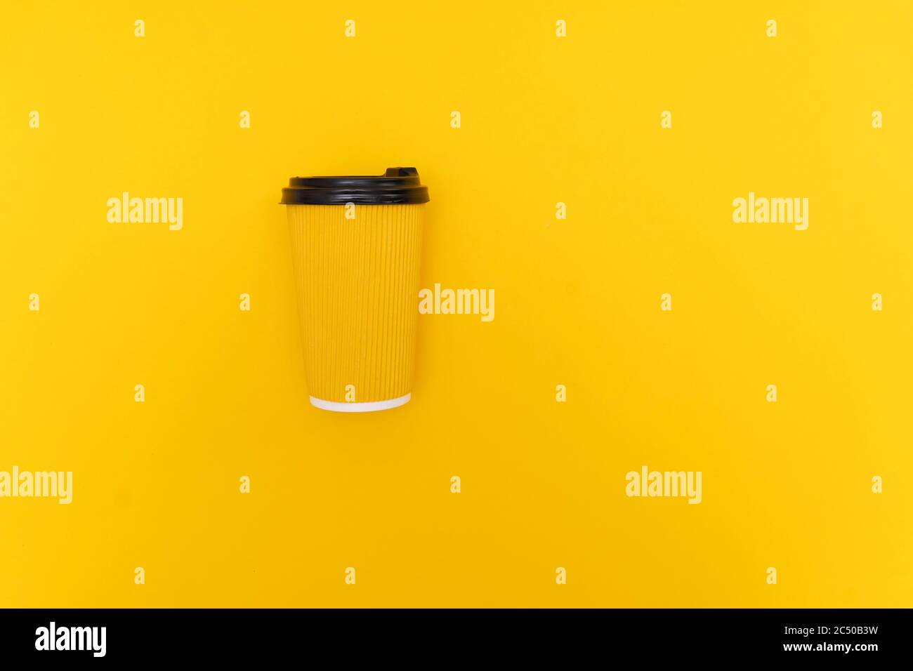 Kaffee zum Mitnehmen in gelber Papiertasse mit schwarzem Deckel auf gelbem Hintergrund Stockfoto