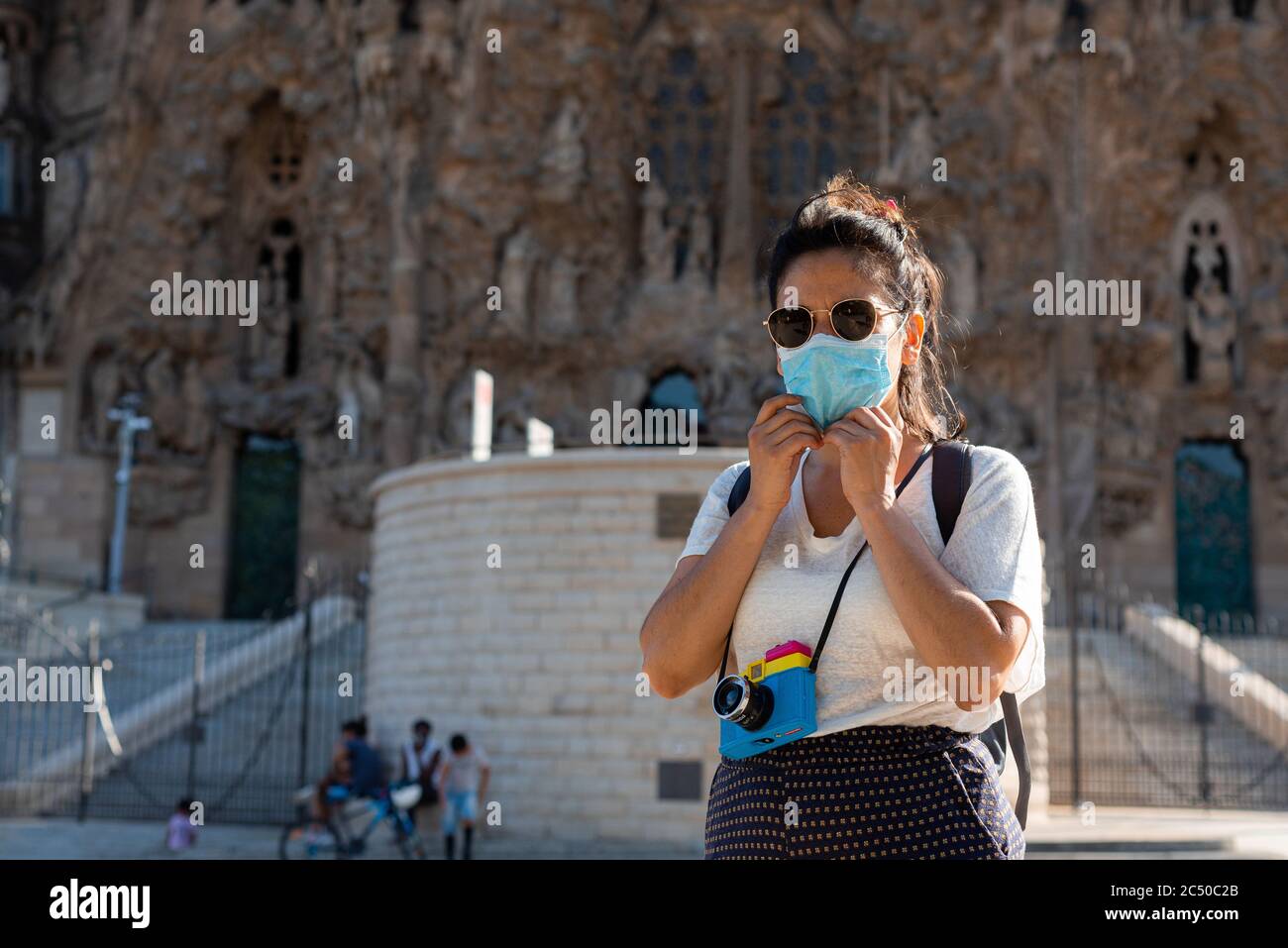 Junge Frau mit Schutzmaske fotografieren mit Kamera und tun Touristen Dinge vor Wahrzeichen Monumente in barcelona, spanien. Tourismus Stockfoto