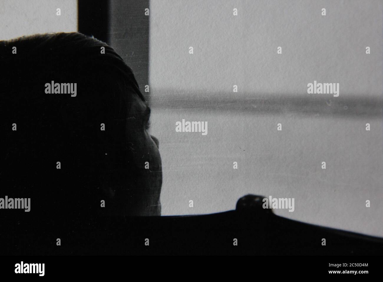 Feine 70s Vintage Schwarz-Weiß-Fotografie einer schönen Frau, die aus dem Fenster starrt. Stockfoto