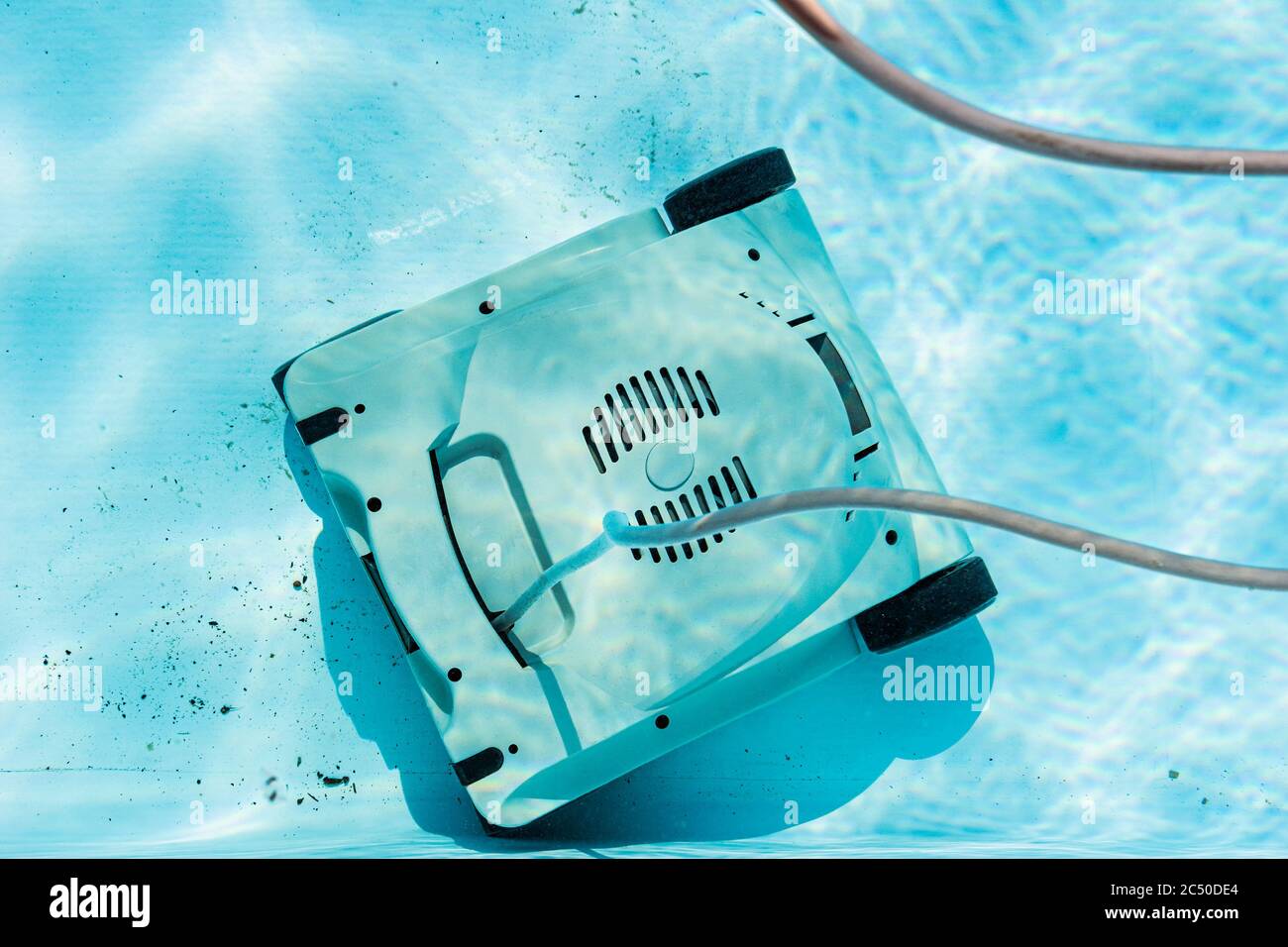 Draufsicht auf einen automatischen Unterwasserroboter-Pool-Staubsauger, der den Schmutz auf dem Boden reinigt. Stockfoto