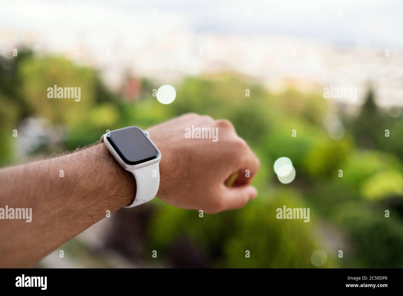 Izmir, Türkei - 11. Juni 2020: Nahaufnahme der Apple-Marke der 5. Generation weiß gefärbte Apple-Uhr auf einem mans-Handgelenk und defokussierten grünen Hintergrund. Stockfoto