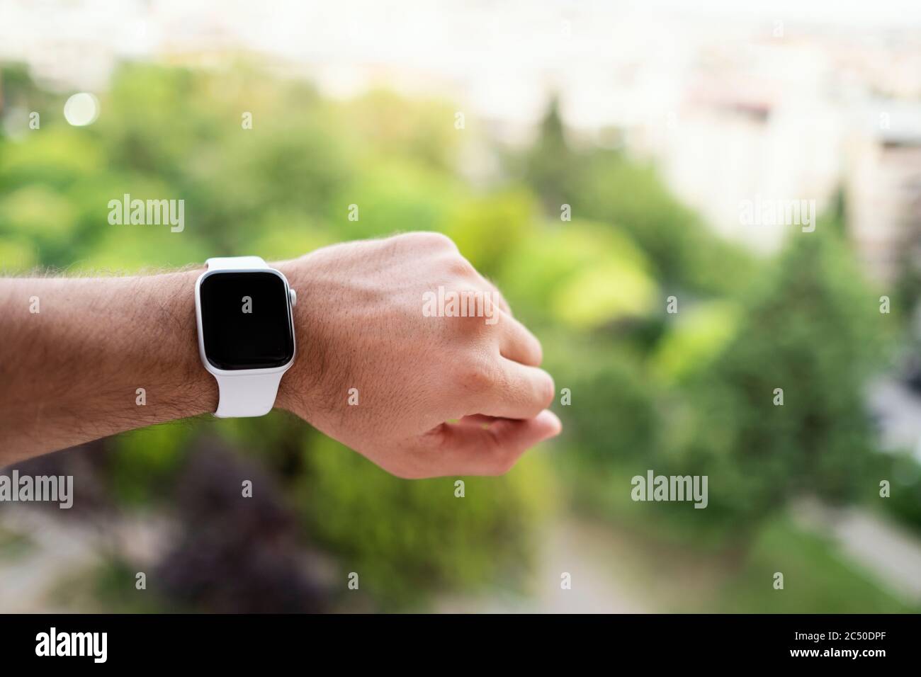 Izmir, Türkei - 11. Juni 2020: Nahaufnahme der Apple-Marke der 5. Generation weiß gefärbte Apple-Uhr auf einem mans-Handgelenk und defokussierten grünen Hintergrund. Stockfoto