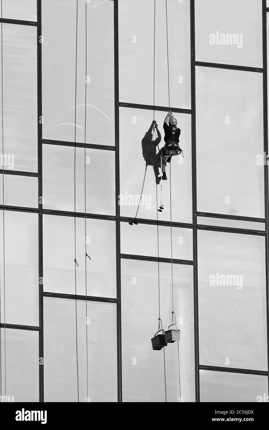 Fensterputzer bei der Arbeit. Fensterreiniger im Aufhängungssystem. Industrieller Bergsport. Stockfoto