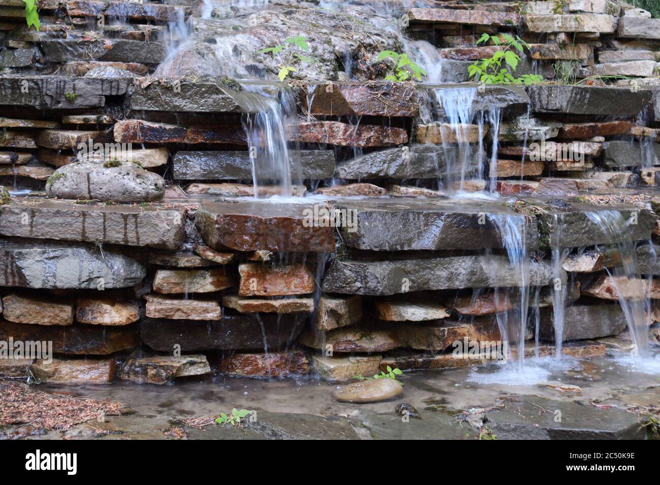Künstlicher Wasserfall im Garten Kaskade mit Steinen gemacht Stockfoto