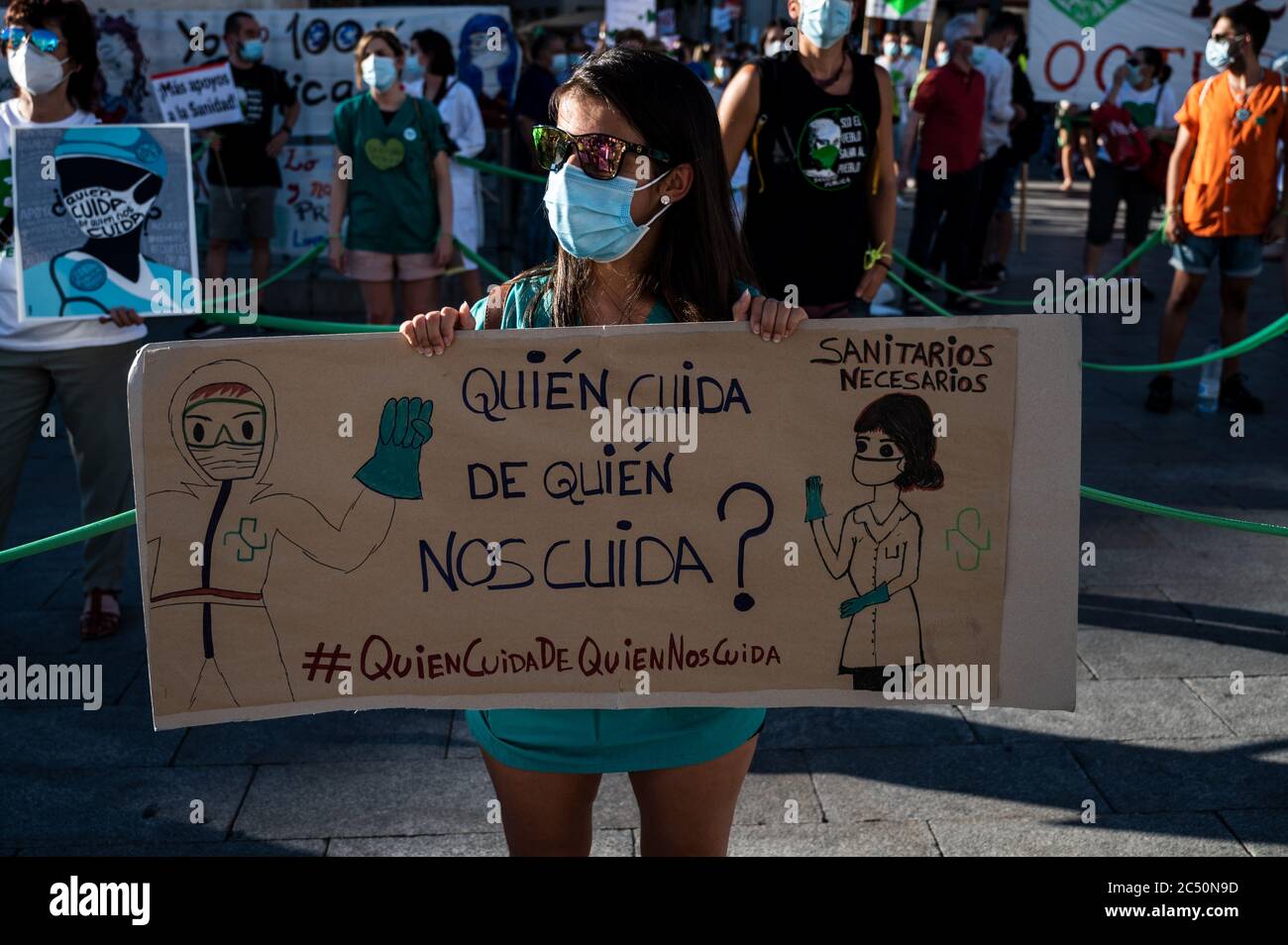 Madrid, Spanien. Juni 2020. Gesundheitshelfer hält ein Plakat mit der Aufschrift: "Wer kümmert sich um diejenigen, die sich um uns kümmern?" Während eines Protestes gegen die Prekarität, den Mangel an Ressourcen und die übermäßige Arbeitsbelastung während der Krise der Coronavirus (COVID-19) Pandemie in öffentlichen Krankenhäusern. Die Gesundheitshelfer des öffentlichen Krankenhauses von Madrid haben sich in der Puerta de Sol versammelt, um ihren Kampf sichtbar zu machen. Quelle: Marcos del Mazo/Alamy Live News Stockfoto
