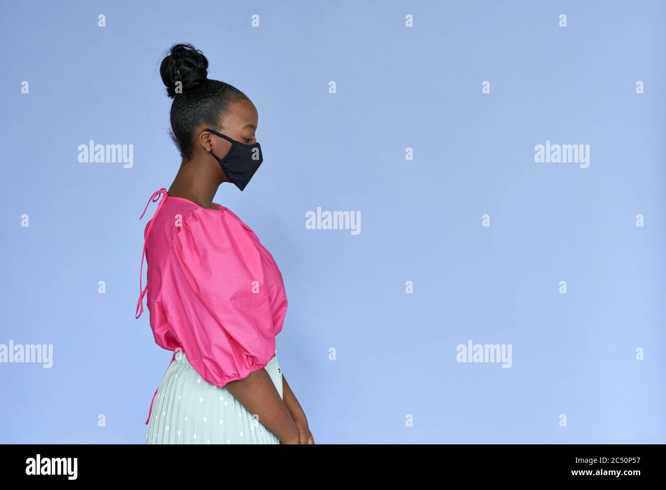 Junge afrikanische Frau trägt stilvolle trendige schwarze Gesichtsmaske isoliert auf Flieder. Stockfoto